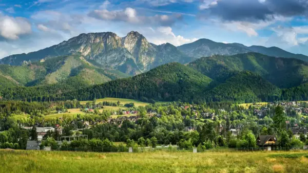 Majestatyczny Giewont, którego wysokość robi wrażenie, góruje nad zieloną doliną pełną domów i lasów.